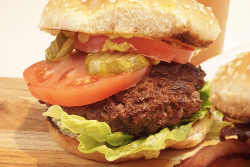 Close up on the ultimate perfect burger with the classic toppings. Lettuce, tomato, and pickles. 