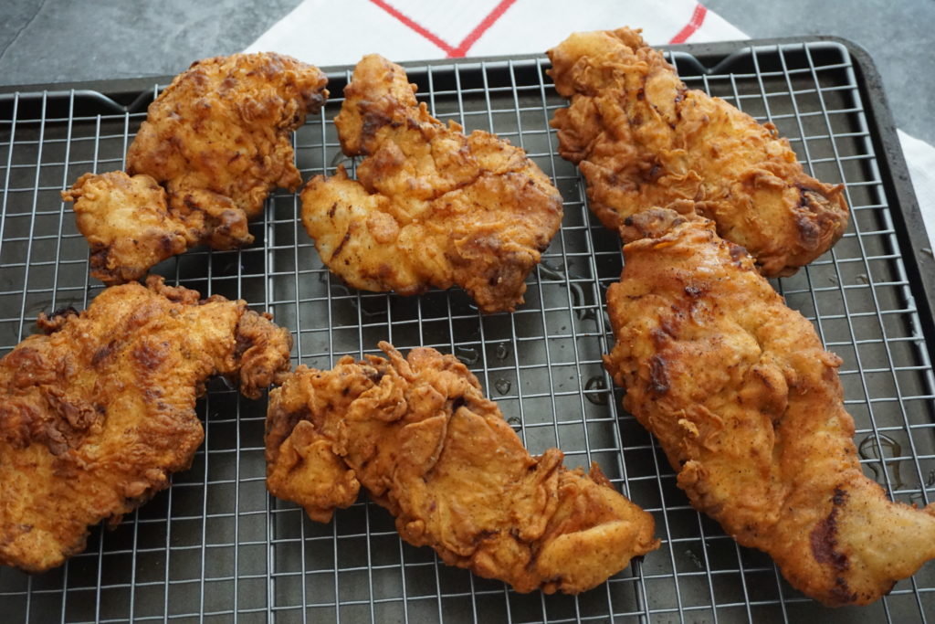 Fried Chicken sandwiches cooling down on a rack.