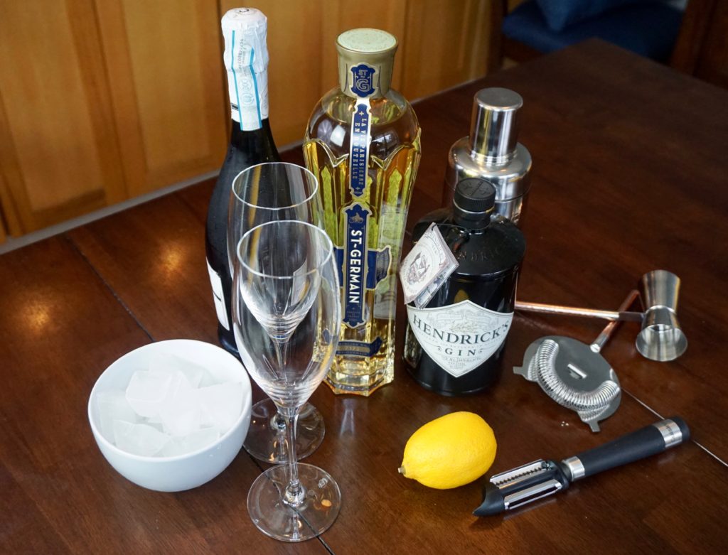 French 77 ingredients: St. Germain, Champagne, lemon, gin, and bar accessories 