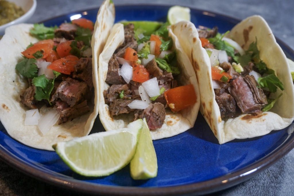 Close of the tacos de carne asada with pico de gallo and wedged limes 