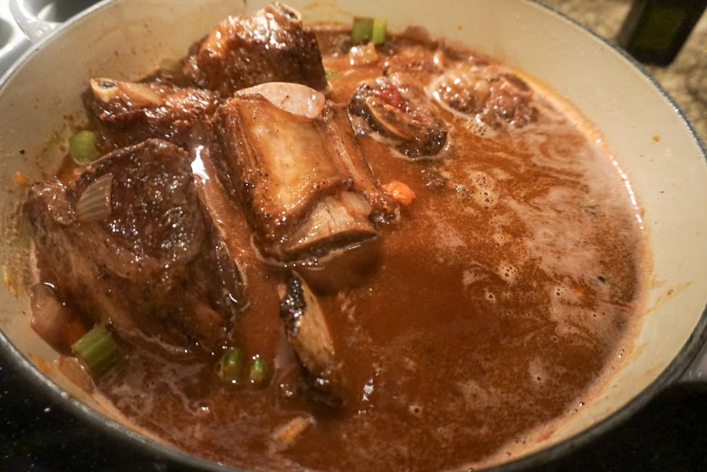Simmering the short ribs in the red wine before adding the stock, garlic, and herbs