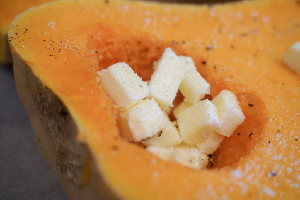 unsalted butter in the cavities of seasoned butternut squash