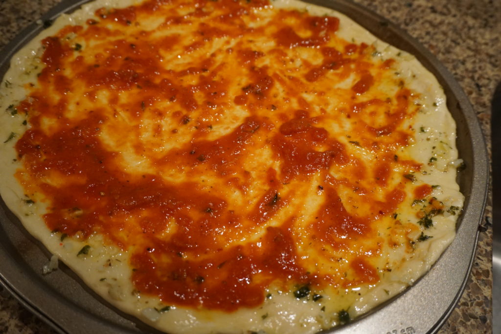 pizza dough with tomato sauce and garlic herb crust