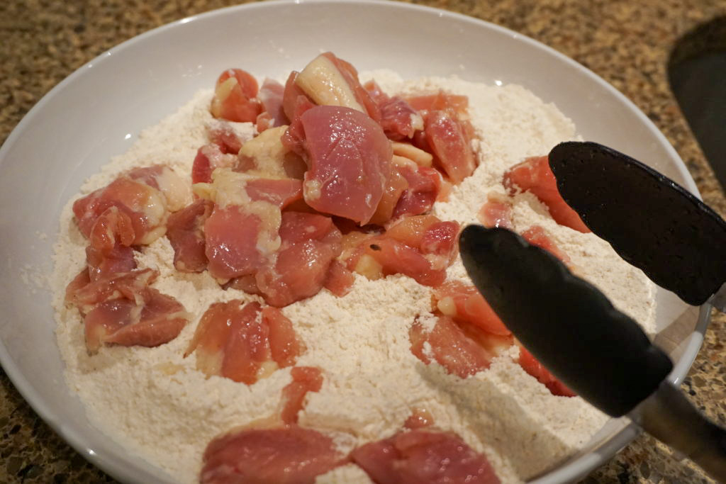 chicken thighs going into the flour mixture