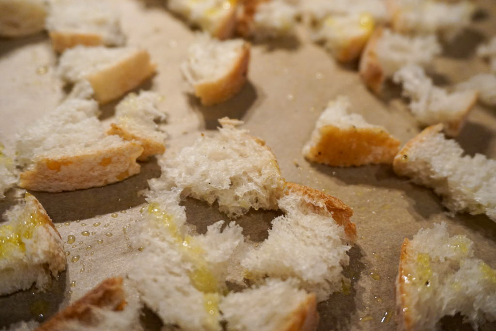 before baking the croutons with the addition of salt, pepper, and olive oil