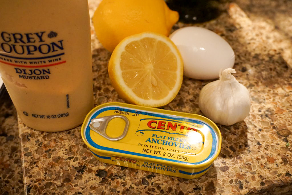 the ingredients for the dressing: garlic, egg, anchovies, lemon juice, dijon mustard