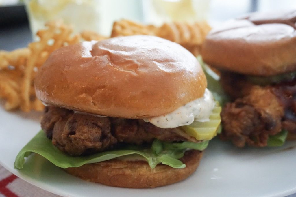 Close up of the fried chicken sandwich with homemade dill sauce. Served with homemade lemonade and waffle fries.