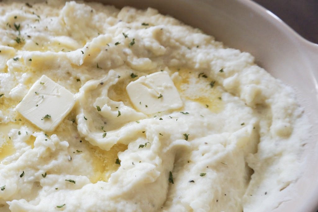 Close up of mashed potatoes with dried parsley and butter 