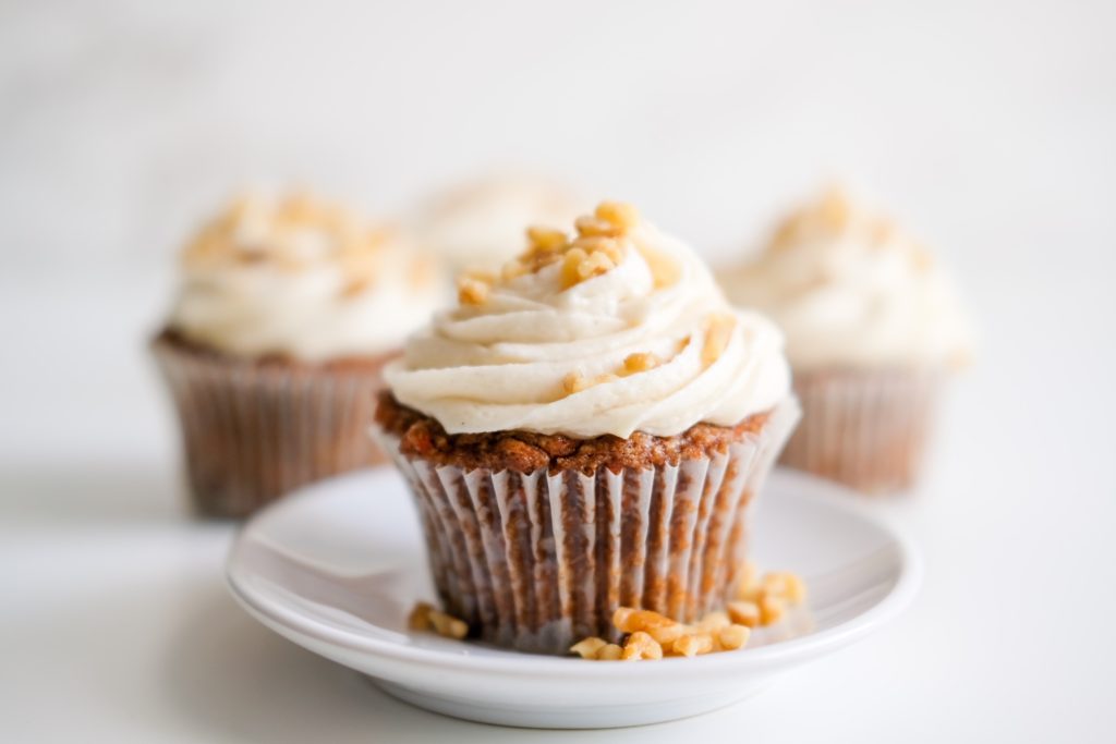 vegan carrot cake cupcakes on a plate with chopped walnuts 