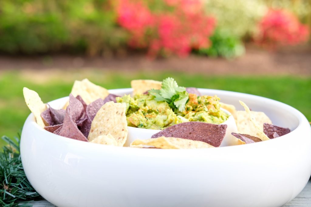 guacamole and tortilla chips in a bowl outside 