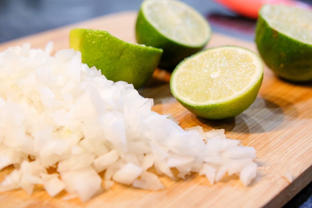 diced onions and fresh limes on a cutting board 