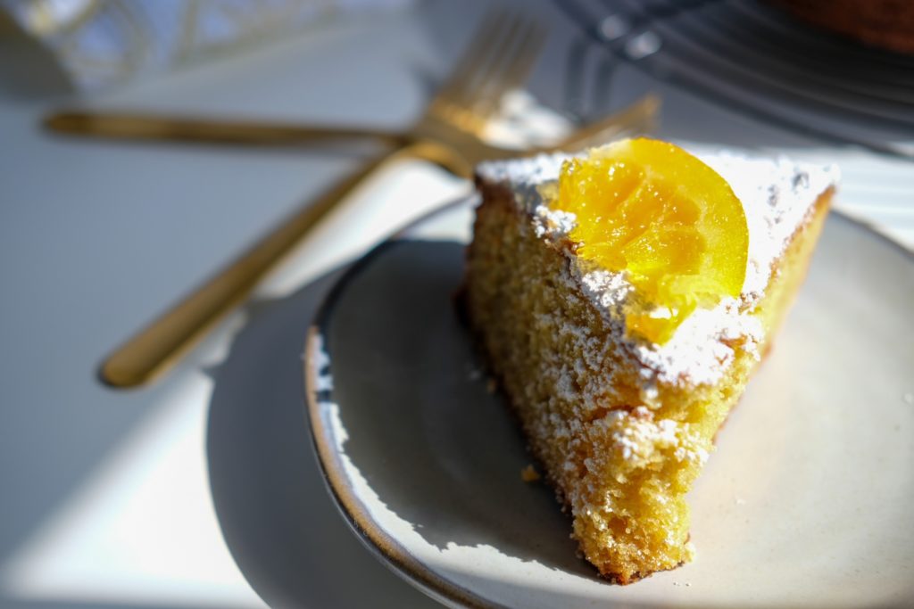 slice of the olive oil cake with candied oranges and powdered sugar on top