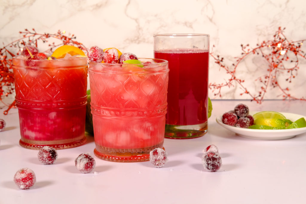 the cocktail with sliced limes and sugared cranberries